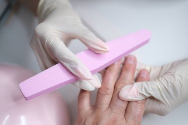 Profesyonel manikür, güzellik salonunda manikür. Eldivenler konusunda ustanın elleri. Tırnaklar parlatılıyor