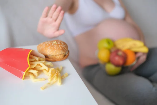 O conceito é gravidez, um estilo de vida saudável, excesso de peso e diabetes. Uma mulher grávida recusa comida de plástico. — Fotografia de Stock