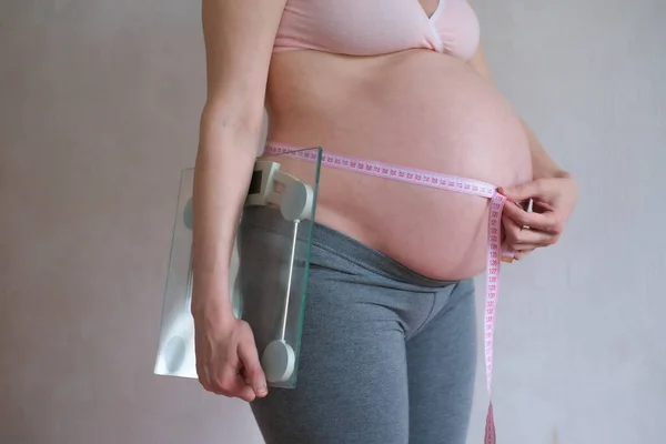 Een zwangere vrouw houdt schubben in haar handen. Concept - voedsel en gezonde levensstijl — Stockfoto