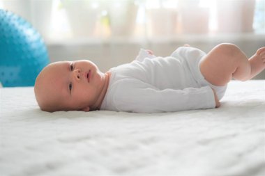 Yeni doğmuş bir bebek beyaz bir battaniyenin üzerinde yatıyor. Bir çocuğun yakın plan portresi.