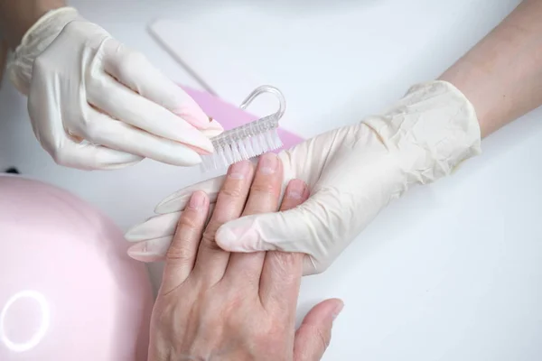 Professional nail care, manicure in a beauty salon. Hands of a master in gloves close-up. Polishing nails — Stock Photo, Image