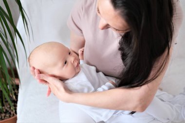 Sevgi dolu anne, yeni doğmuş bebeğini evde taşıyor. Mutlu bir annenin parlak bir portresi.. 