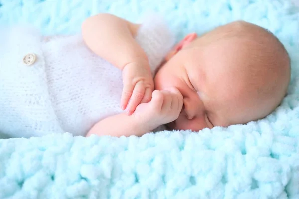 En sovande nyfödd pojke eller flicka ligger på en blå ullfilt.Närbild porträtt av ett barn — Stockfoto