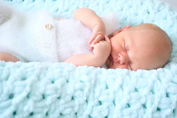 Seorang anak laki-laki atau perempuan yang baru lahir tertidur terletak pada selimut wol biru. Foto dekat seorang anak — Stok Foto