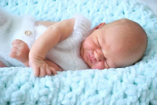 A sleeping newborn boy or girl lies on a blue wool blanket.Close-up portrait of a child — Stock Photo, Image