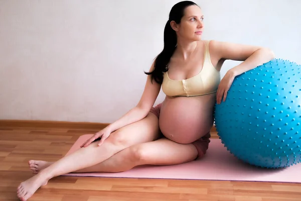 Uma mulher grávida entra para esportes com uma bola de fitness e ioga. Conceito de comida, estilo de vida saudável. — Fotografia de Stock