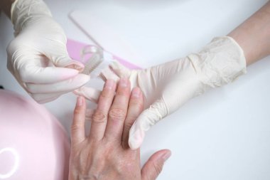 Profesyonel manikür, güzellik salonunda manikür. Eldivenler konusunda ustanın elleri. Tırnaklar parlatılıyor