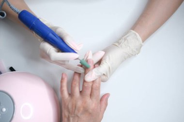 Tırnak bakımı. Usta manikür sırasında ojeli elleri kesmek için elektrikli makine kullanıyor..