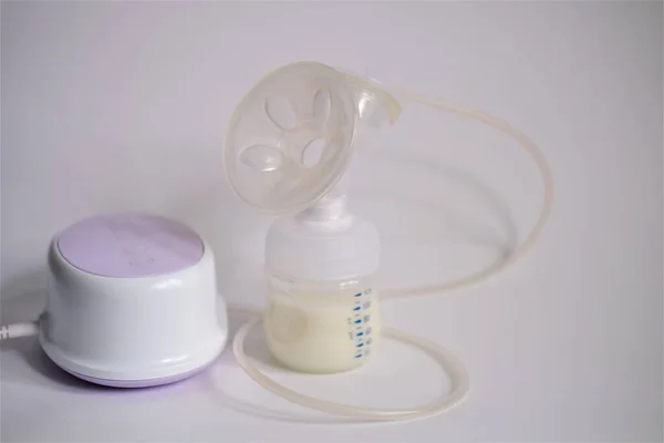 The electric breast pump is on the table in the kitchen. Give expressed breast milk. Breast care for a young mother