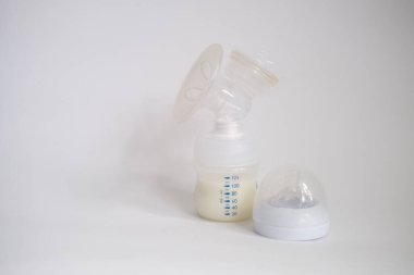 Elektrikli göğüs pompası mutfaktaki masanın üzerinde. İfade edilmiş anne sütü. Genç bir anneye meme bakımı.