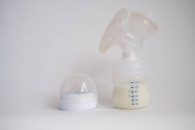 Elektrikli göğüs pompası mutfaktaki masanın üzerinde. İfade edilmiş anne sütü. Genç bir anneye meme bakımı.