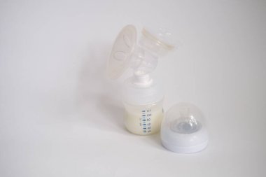 Elektrikli göğüs pompası mutfaktaki masanın üzerinde. İfade edilmiş anne sütü. Genç bir anneye meme bakımı.