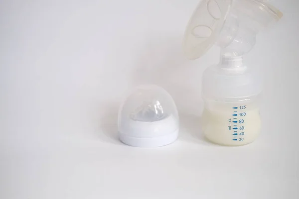 Elektrikli göğüs pompası mutfaktaki masanın üzerinde. İfade edilmiş anne sütü. Genç bir anneye meme bakımı.