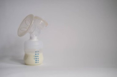 Elektrikli göğüs pompası mutfaktaki masanın üzerinde. İfade edilmiş anne sütü. Genç bir anneye meme bakımı.