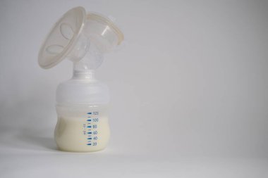 Elektrikli göğüs pompası mutfaktaki masanın üzerinde. İfade edilmiş anne sütü. Genç bir anneye meme bakımı.