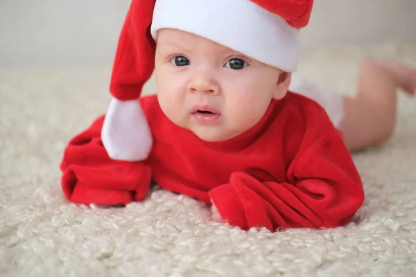 Beyaz arka planda Noel Baba kostümlü bebek. Noel Baba kostümlü sürünen bebek.