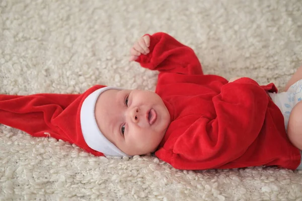 Kırmızı kostümlü ve şapkalı bebek. Güzel küçük bebek Noel 'i kutluyor.