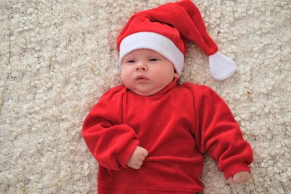 Weihnachtsmann-Baby liegt auf weißer Decke Weihnachten Kleinkind in Weihnachtsmütze — Stockfoto
