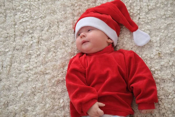 Weihnachtsmann-Baby liegt auf weißer Decke Weihnachten Kleinkind in Weihnachtsmütze — Stockfoto