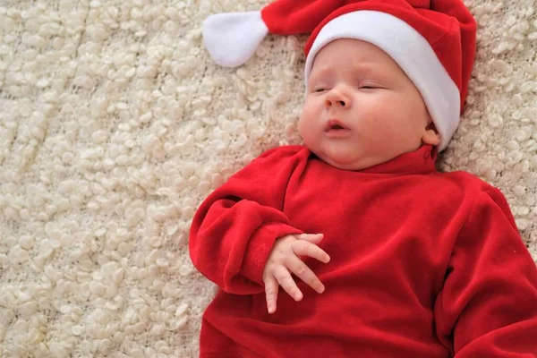 Mikołaj dziecko leżące na białym kocu Boże Narodzenie maluch w Santa kapelusz — Zdjęcie stockowe