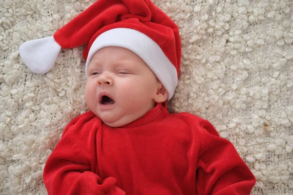 Santa Claus dítě ležící na bílé přikrývce Vánoční batole v Santa klobouk — Stock fotografie