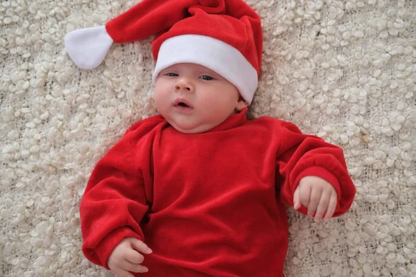 Weihnachtsmann-Baby liegt auf weißer Decke Weihnachten Kleinkind in Weihnachtsmütze — Stockfoto