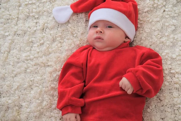 Weihnachtsmann-Baby auf weißer Decke liegend. Schönes kleines Baby feiert Weihnachten. — Stockfoto