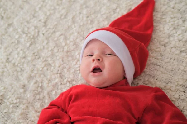 Babbo Natale bambino sdraiato sulla coperta bianca. Bellissimo bambino festeggia il Natale. — Foto Stock