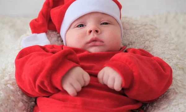 Beyaz arka planda Noel Baba kostümlü bebek. Noel Baba şapkalı bebek.