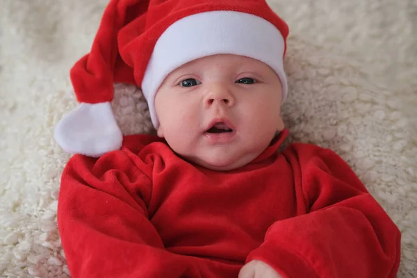 Baby im Weihnachtsmannkostüm auf weißem Hintergrund. Weihnachtskind mit Weihnachtsmütze — Stockfoto