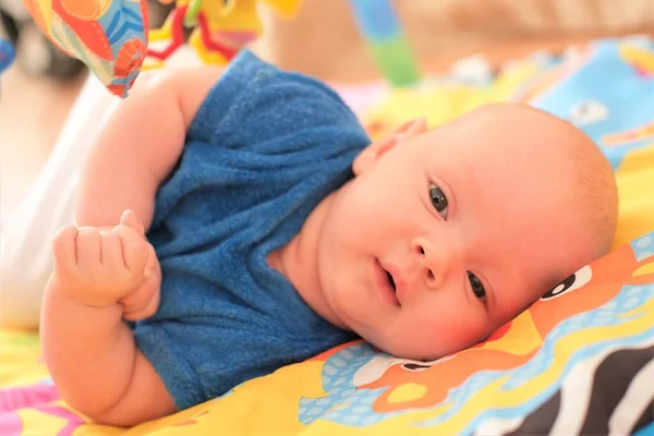 新生男婴或女婴在玩耍。一个可爱的3个月大的婴儿躺在明亮的毛毯上的画像. — 图库照片