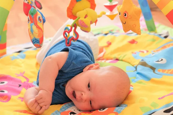 Neugeborene Jungen oder Mädchen spielen. Porträt eines süßen 3 Monate alten Babys, das auf einer hellen Decke liegt. — Stockfoto
