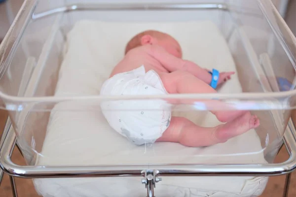 Neugeborenes - ein Junge oder ein Mädchen in einer Geburtsklinik schläft in einem Kinderbett, Konzept - Gesundheitsfürsorge und Medizin. — Stockfoto