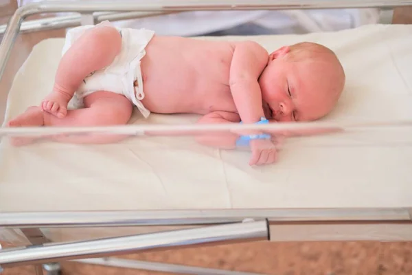 Neugeborenes - ein Junge oder ein Mädchen in einer Geburtsklinik schläft in einem Kinderbett, Konzept - Gesundheitsfürsorge und Medizin. — Stockfoto