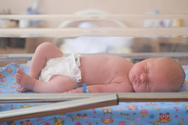 Neugeborenes - ein Junge oder ein Mädchen in einer Geburtsklinik schläft in einem Kinderbett, Konzept - Gesundheitsfürsorge und Medizin. — Stockfoto