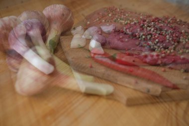 Çiğ taze et üzerine renkli biber ve marine edilmiş et serpiştirilir. Ahşap kesme tahtasının üzerinde baharatlı ızgara biftek.