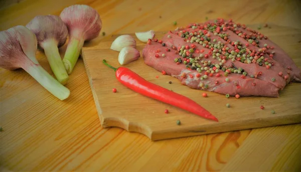 Rohes frisches Fleisch wird mit farbigen Paprika bestreut und mariniert. Gegrilltes Rindersteak mit Gewürzen auf einem Holzschneidebrett — Stockfoto