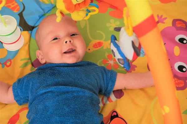 这个新生婴儿在笑.一个可爱的3个月大的婴儿躺在明亮的毛毯上的画像 — 图库照片