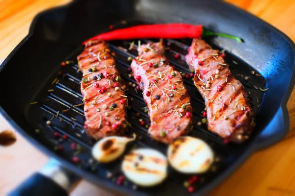 Grilled beef or pork steak with onion and pepper on a grill pan.Grilled meat close up — Stock Photo, Image