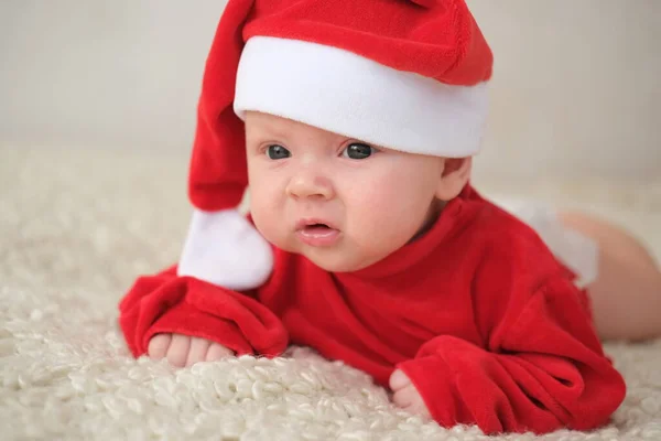 Beyaz arka planda Noel Baba kostümlü bebek. Noel Baba kostümlü sürünen bebek.