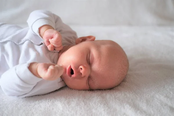 하얀 담요 위에서 자고 있는 소염이 있는 갓난아기의 모습. — 스톡 사진