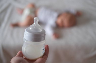 Uyuyan bir bebeğin arka planında bir şişe süt. Kavram - emzirme.