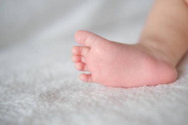 Beyaz bir battaniyenin arka planında bebek ayakları var..