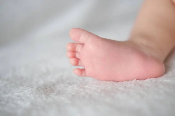 Babyfüße aus nächster Nähe auf dem Hintergrund einer weißen Decke. — Stockfoto