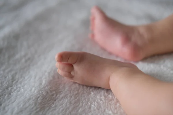 Baby feet close-up on the background of a white blanket. — Stock Photo, Image