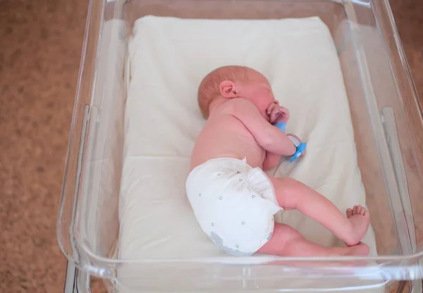 Neugeborenes - ein Junge oder ein Mädchen in einer Geburtsklinik schläft in einem Kinderbett, Konzept - Gesundheitsfürsorge und Medizin. — Stockfoto