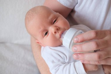 Bir baba yeni doğmuş bebeğini kucağına alıp besler. Bebeğin yüzünde ve kafasında irin var..