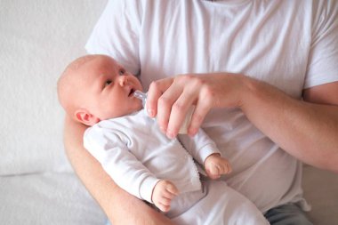Bir baba yeni doğmuş bebeğini kucağına alıp besler. Bebeğin yüzünde ve kafasında irin var..
