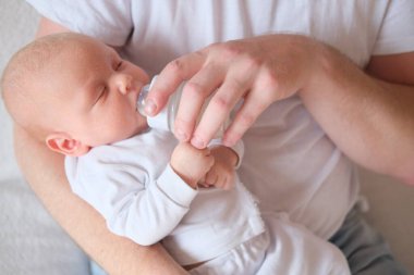 Bir baba yeni doğmuş bebeğini kucağına alıp besler. Bebeğin yüzünde ve kafasında irin var..