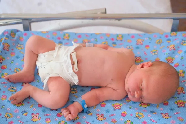 Neugeborenes - ein Junge oder ein Mädchen in einer Geburtsklinik schläft in einem Kinderbett, Konzept - Gesundheitsfürsorge und Medizin. — Stockfoto